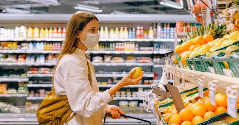 woman in the grocery holding an orange